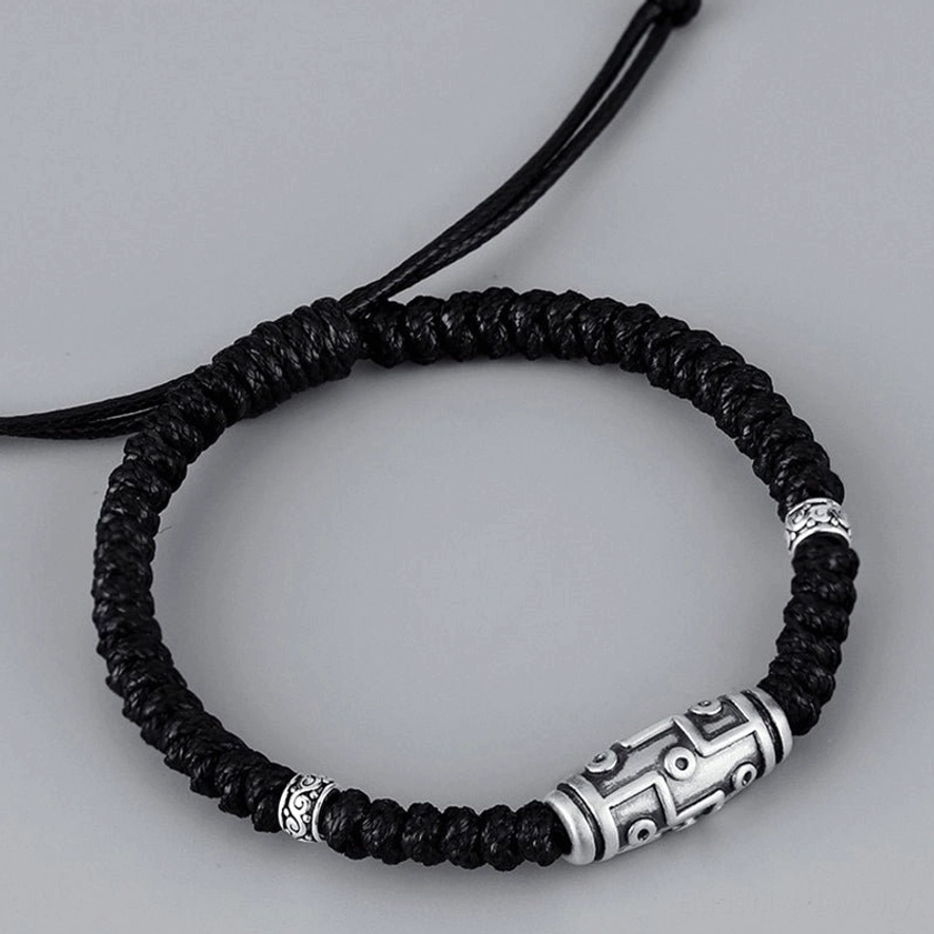 Flat overhead view of adjustable nine-eye dzi sterling silver bracelet with drawstring design and decorative silver end beads