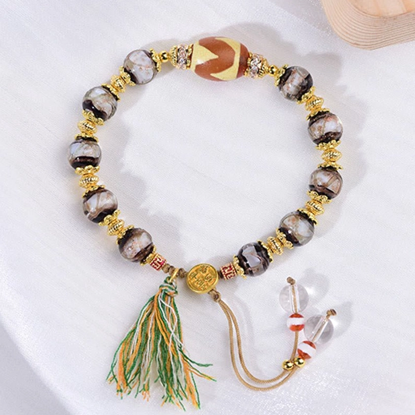 Adjustable sacred dzi bracelet with multiple bead styles and protective amulet properties on neutral background