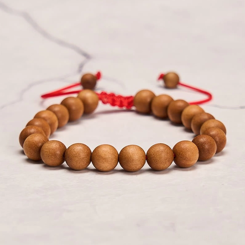 Adjustable sandalwood mala bracelet featuring round sandalwood beads with red braided adjustable cord