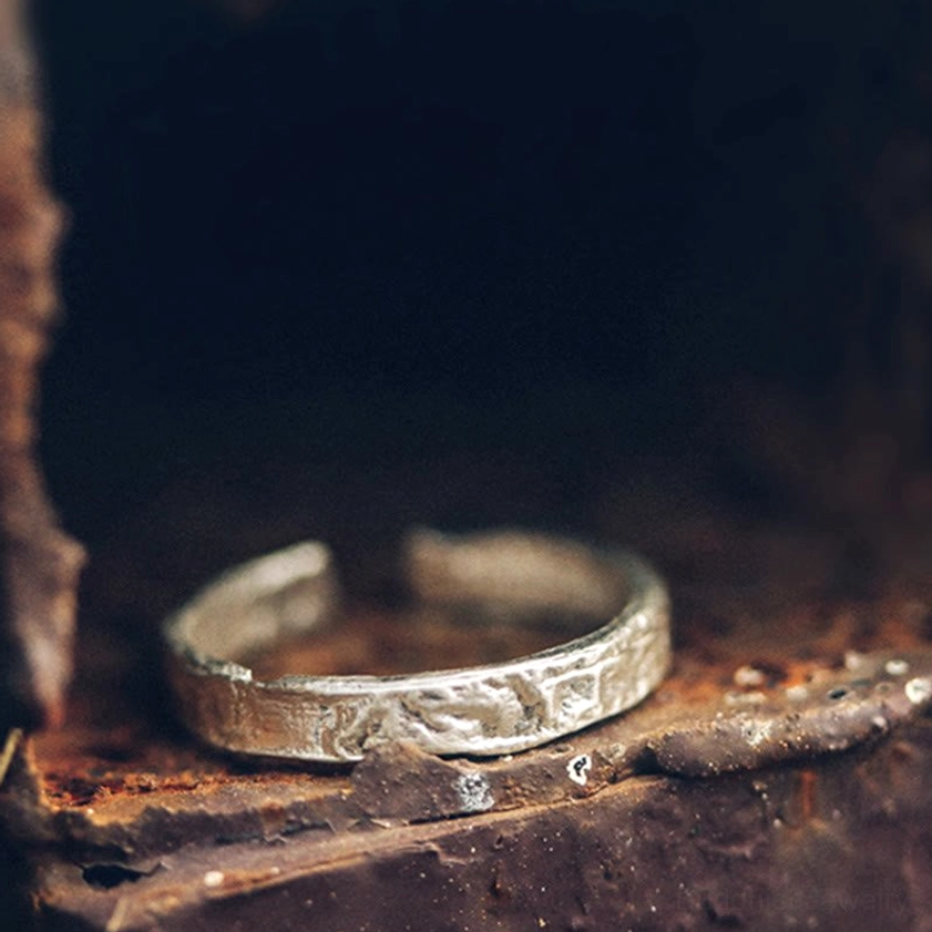 Open adjustable sterling silver ring with embossed rugged texture, side profile close-up