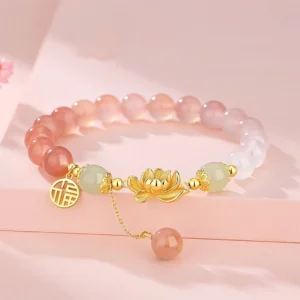 Gradient agate and Hetian jade Buddhist bracelet with lotus and Fu character charm in 925 sterling silver, displayed on pink surface with cherry blossom decoration