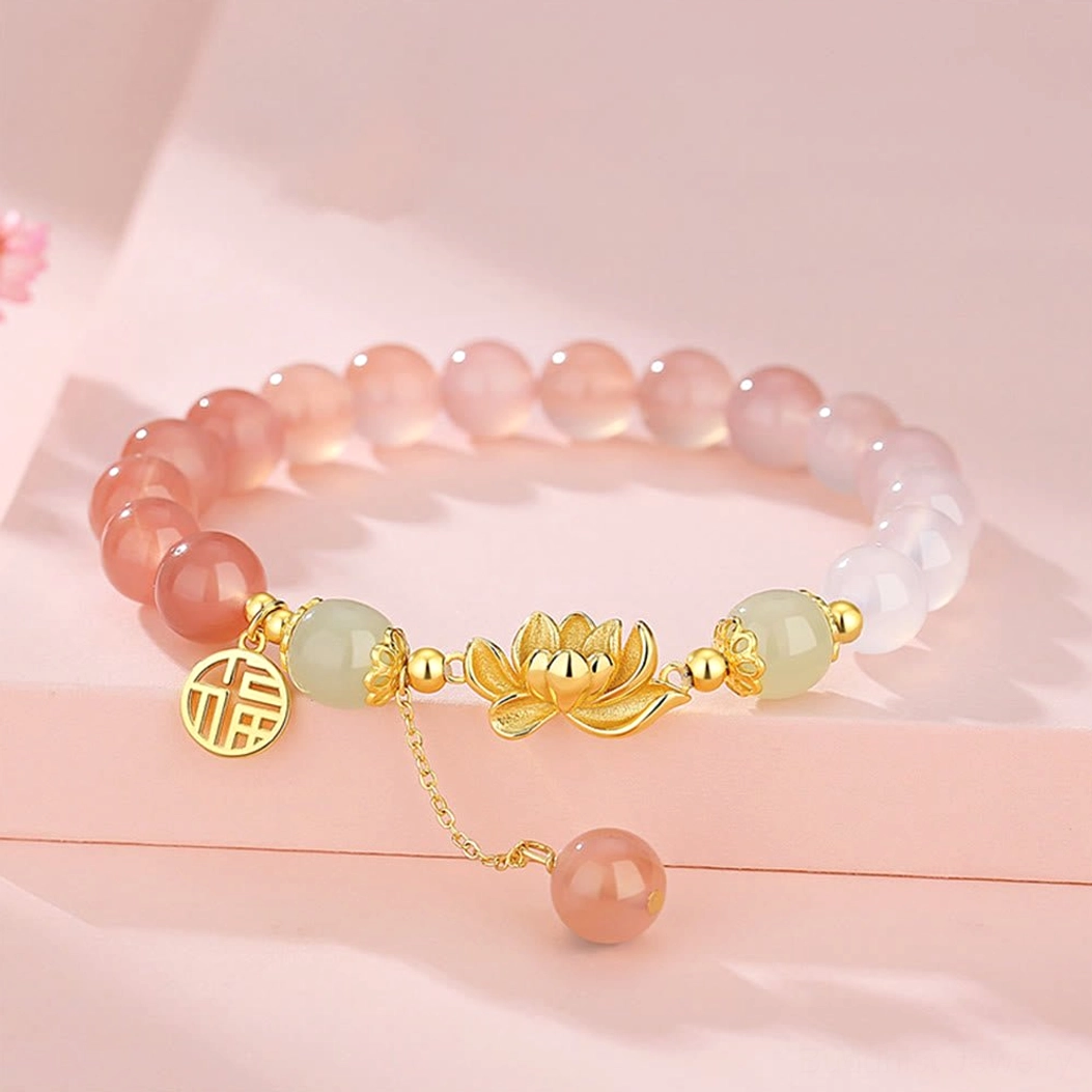 Gradient agate and Hetian jade Buddhist bracelet with lotus and Fu character charm in 925 sterling silver, displayed on pink surface with cherry blossom decoration