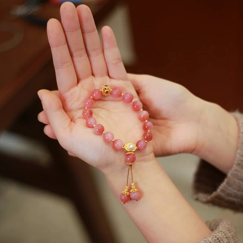 Yanyuan agate lotus beaded bracelet held in palms showing full strand with tassel charm