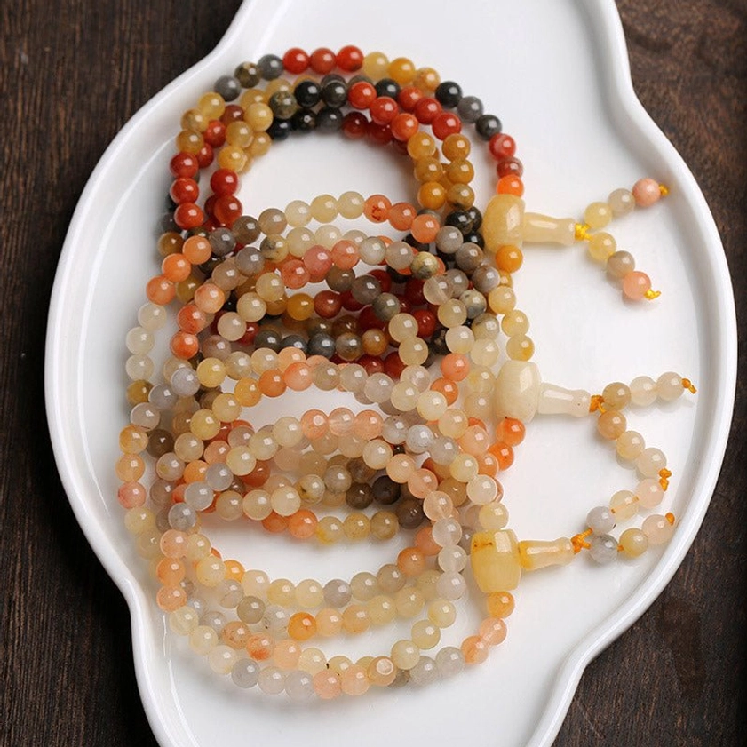 Multiple 108 bead Buddhist mala bracelets collection with jade tassel accents on white ceramic plate