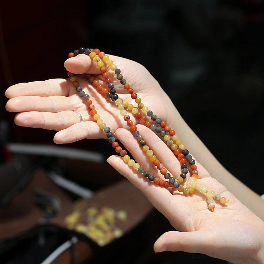 Open palms holding agate mala beads showing warm toned mixed color stone beads - close up hand view