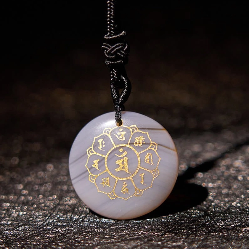 Agate Om Mani Padme Hum Buddhist necklace pendant with gold Sanskrit engraving on natural background