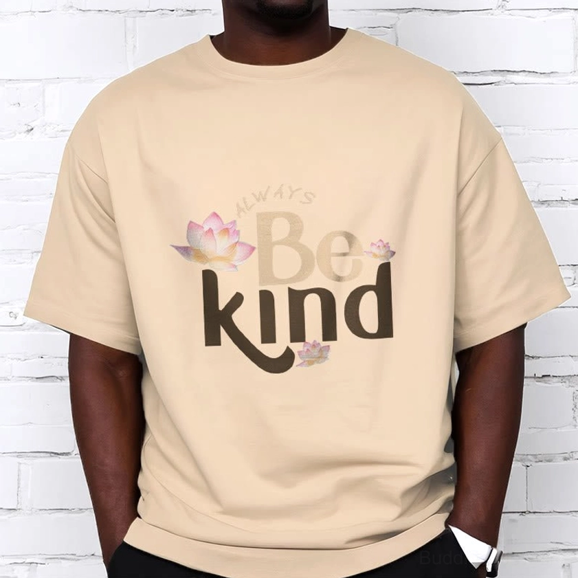Male model wearing khaki beige Always Be Kind Buddhist T-Shirt with relaxed fit, white brick wall