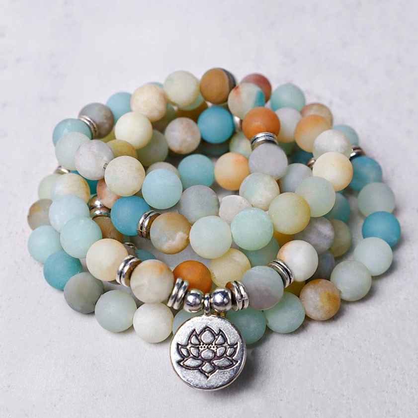 Amazonite lotus prayer mala with 108 beads in overhead flat lay, showing mixed blue and earthy tone stone beads with silver lotus charm and spacers