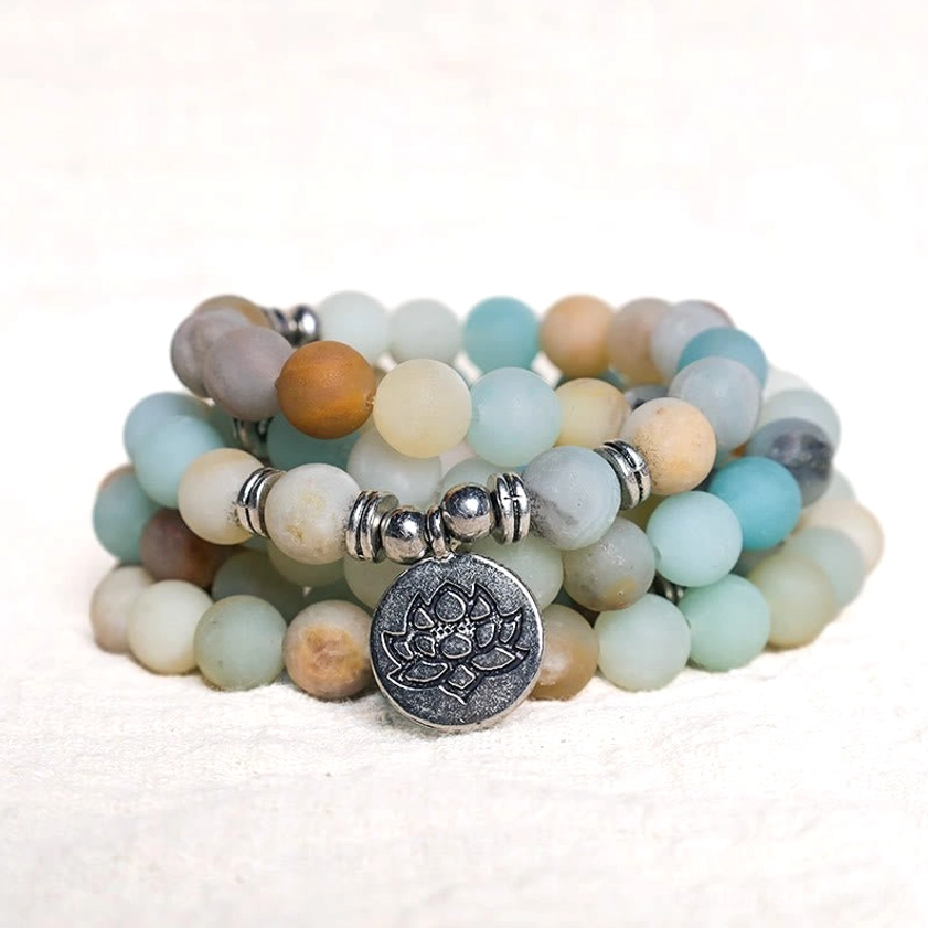 Stacked amazonite lotus mala bracelets in close-up three-quarter view, showing mixed blue beige brown matte beads with silver lotus charm detail
