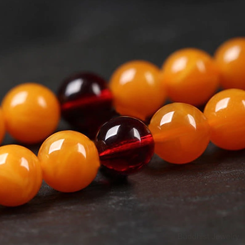 Close-up of polished amber round beads and dark red spacer beads showing smooth glossy finish