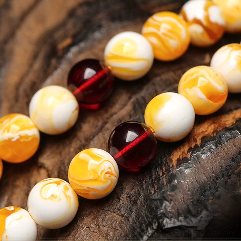 Close-up detailed view amber mala beads veined milky white and golden yellow with dark red spacers