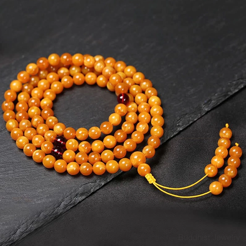Long amber round bead mala strand with yellow tassel, traditional 108-bead Buddhist prayer bracelet