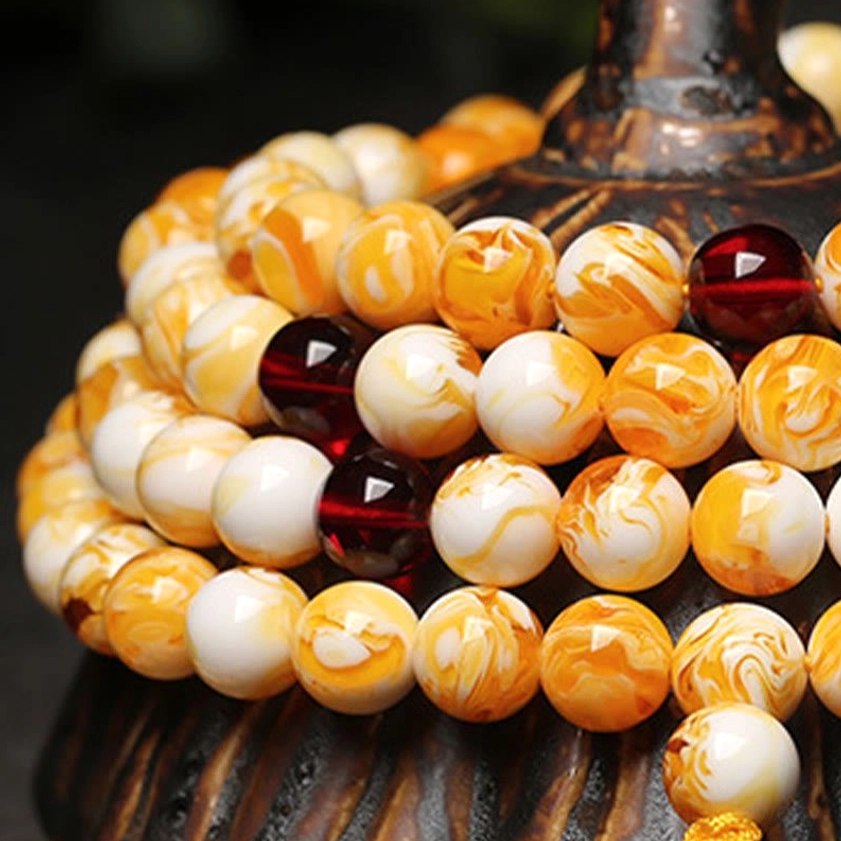 Stacked amber mala beads close-up wooden stand richly veined white and amber beads with spacers