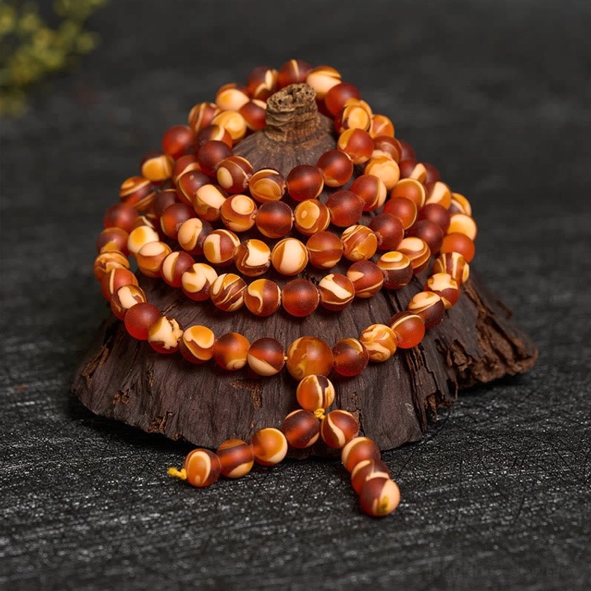 Coiled amber mala beads close-up showing two-tone brown beige round beads with tassel