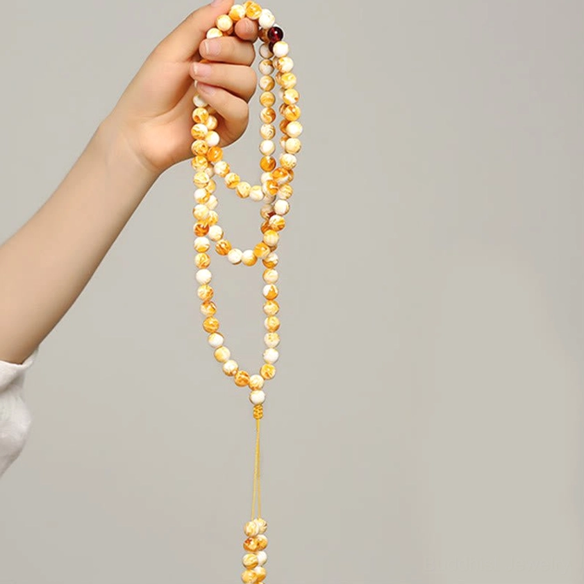 Long 108 bead amber mala necklace hand-held side view white background gradient beads