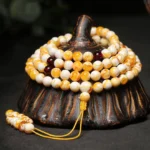 108 bead amber mala necklace wooden display stand top-down view with milky white and golden amber beads