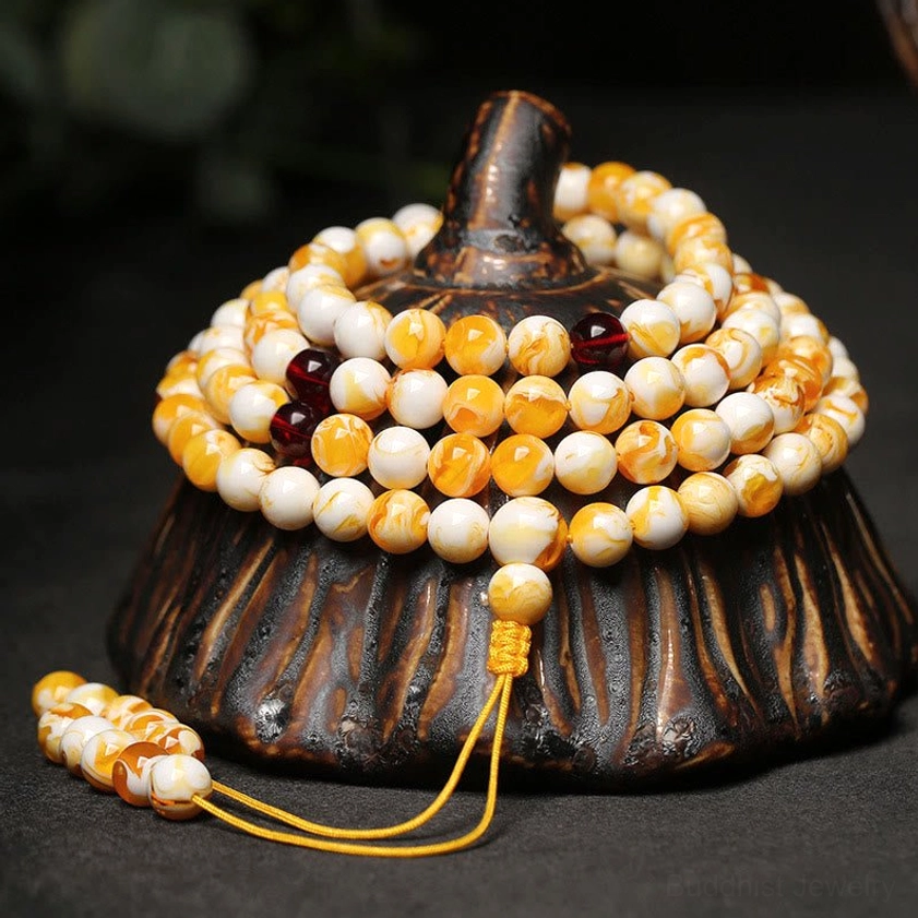 108 bead amber mala necklace wooden display stand top-down view with milky white and golden amber beads