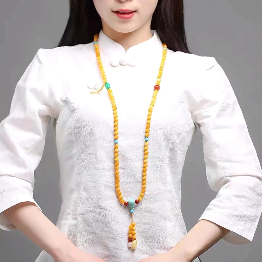 Woman wearing long amber Buddhist mala necklace as everyday spiritual accessory with traditional white shirt