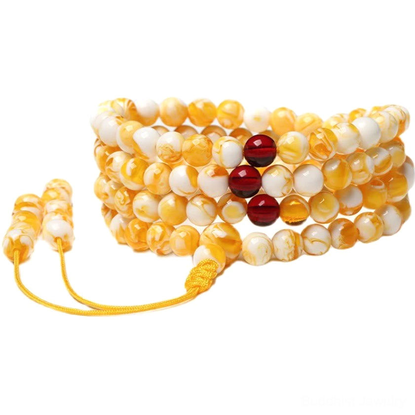 Multiple sets of 108 bead amber mala necklaces flat lay black background yellow tassel cord