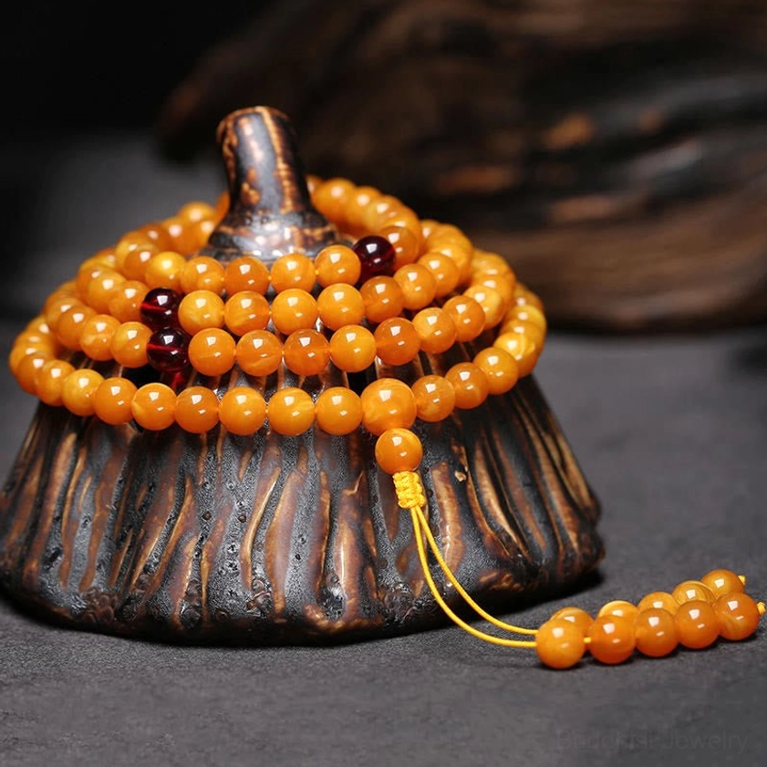 Stacked amber Buddhist mala bracelet 108 beads with dark red spacer bead and golden yellow tassel accent