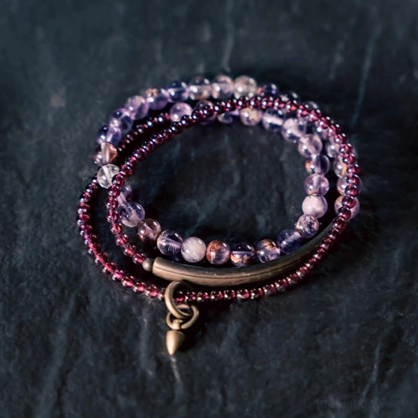 Layered gemstone wrap bracelet set with amethyst and garnet beads from flat lay perspective, featuring faceted purple and red stones with metal accent bar