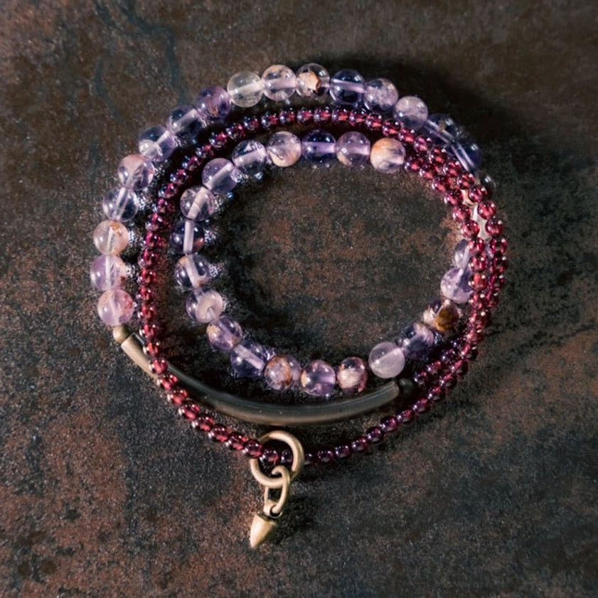 Stacked amethyst garnet beaded bracelets overhead close-up showing mixed clear purple and deep red gem beads with gold hardware