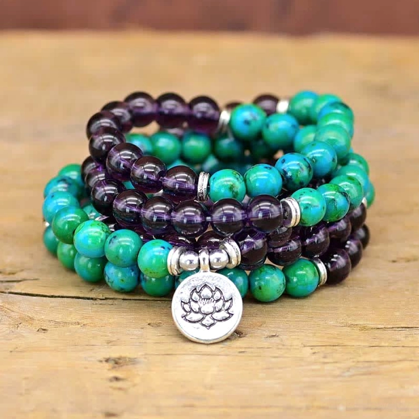 Amethyst and green aventurine lotus bracelet with silver pendant displayed on wooden surface, showing dual-strand spiritual design