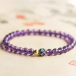 Natural amethyst lotus bracelet with 4mm purple crystal beads and lotus charm, displayed in flat lay on minimal background
