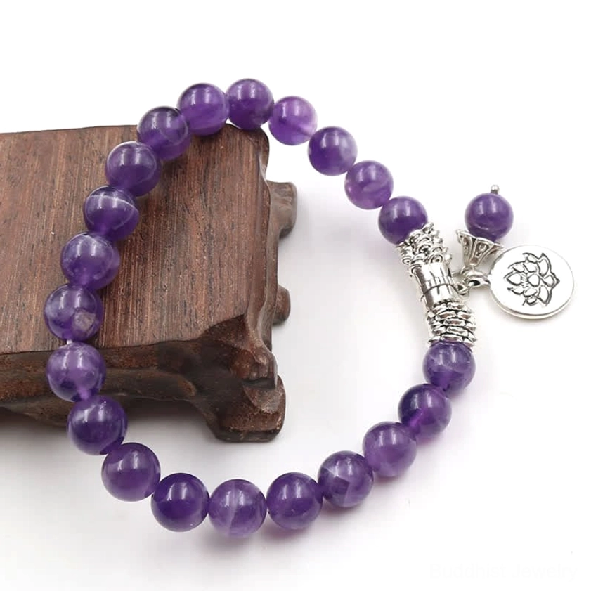Amethyst healing bracelet oblique angle on stand displaying round purple beads with silver spacer components and single lotus pendant