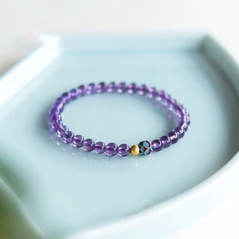 Close-up top view of amethyst beaded bracelet showing smooth purple crystal beads and decorative copper spacer details