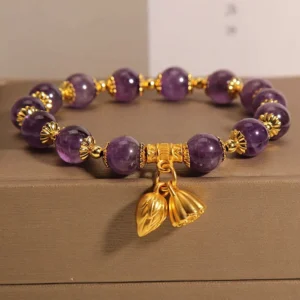 Natural amethyst lotus bracelet flat lay with purple amethyst beads, gold lotus pendants on brown jewelry box