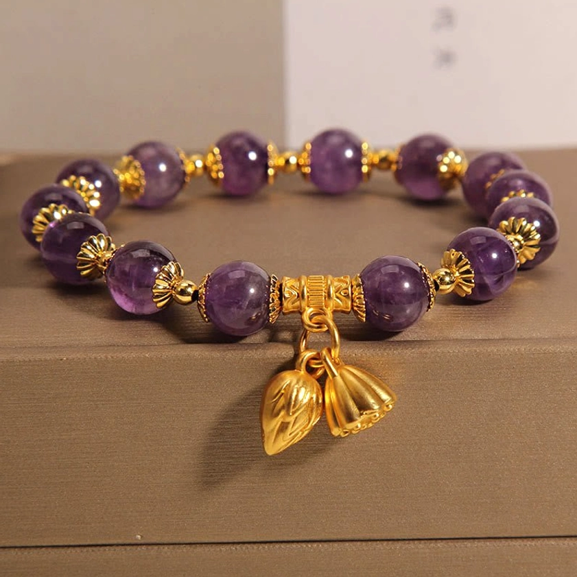 Natural amethyst lotus bracelet flat lay with purple amethyst beads, gold lotus pendants on brown jewelry box