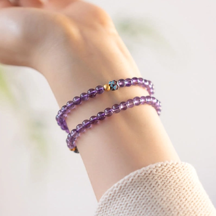 Double-layer amethyst bracelet stack with enamel gold spacer beads and purple crystal strands worn on wrist