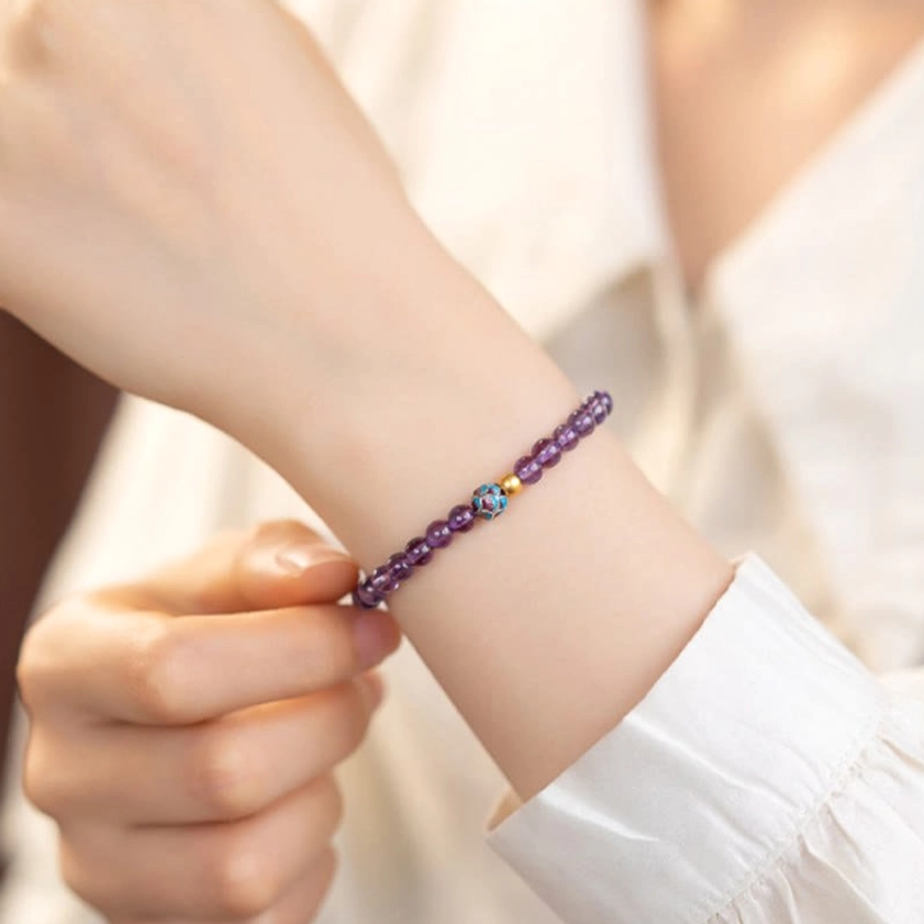 Single amethyst lotus bracelet worn on wrist showing elastic fit and decorative spacer beads with purple crystals