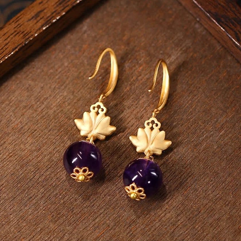 Amethyst lotus drop earrings flat lay featuring matte gold lotus charm and smooth purple amethyst stone