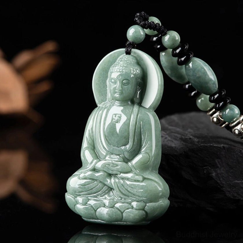 Amitabha Buddha jade amulet three-quarter side view on black stone, showing smooth polished jade texture with attached beaded chain