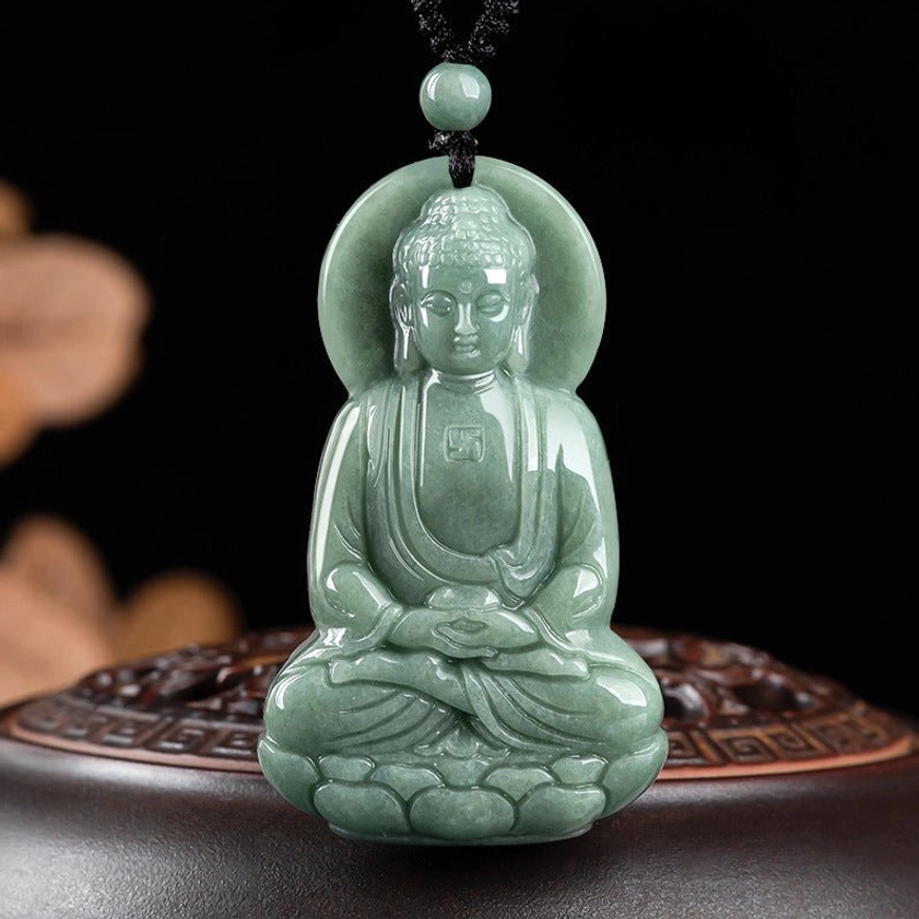 Amitabha Buddha jade pendant front view displayed on carved wooden base, showing green jade with lotus pedestal and chest swastika carving