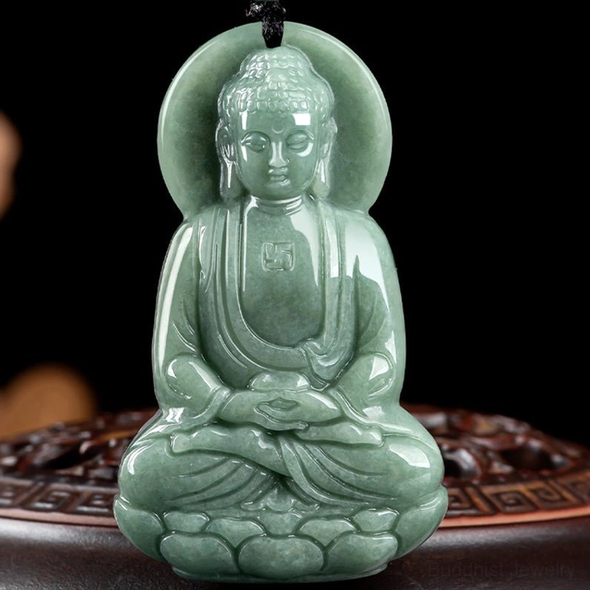Amitabha Buddha jade pendant front close-up on carved wooden background, showcasing full frontal Buddha carving with intricate robe details