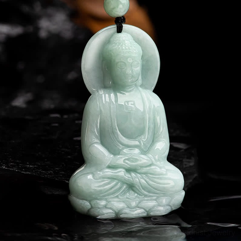 Amitabha Buddha jade pendant front view on dark wet surface, showing lighter green jade tone and seated meditation pose