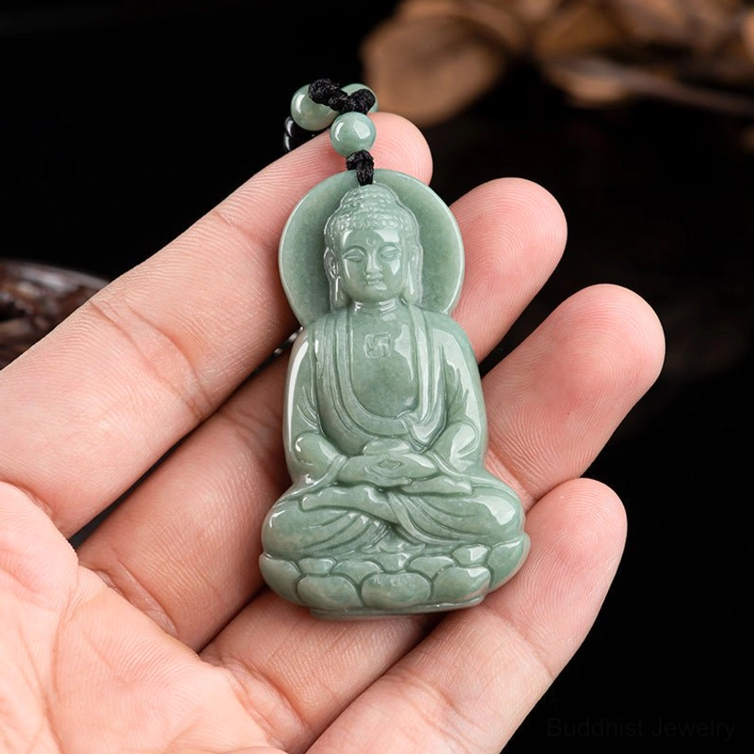 Amitabha Buddha jade pendant handheld close-up in palm, compact standard carving showing intricate details