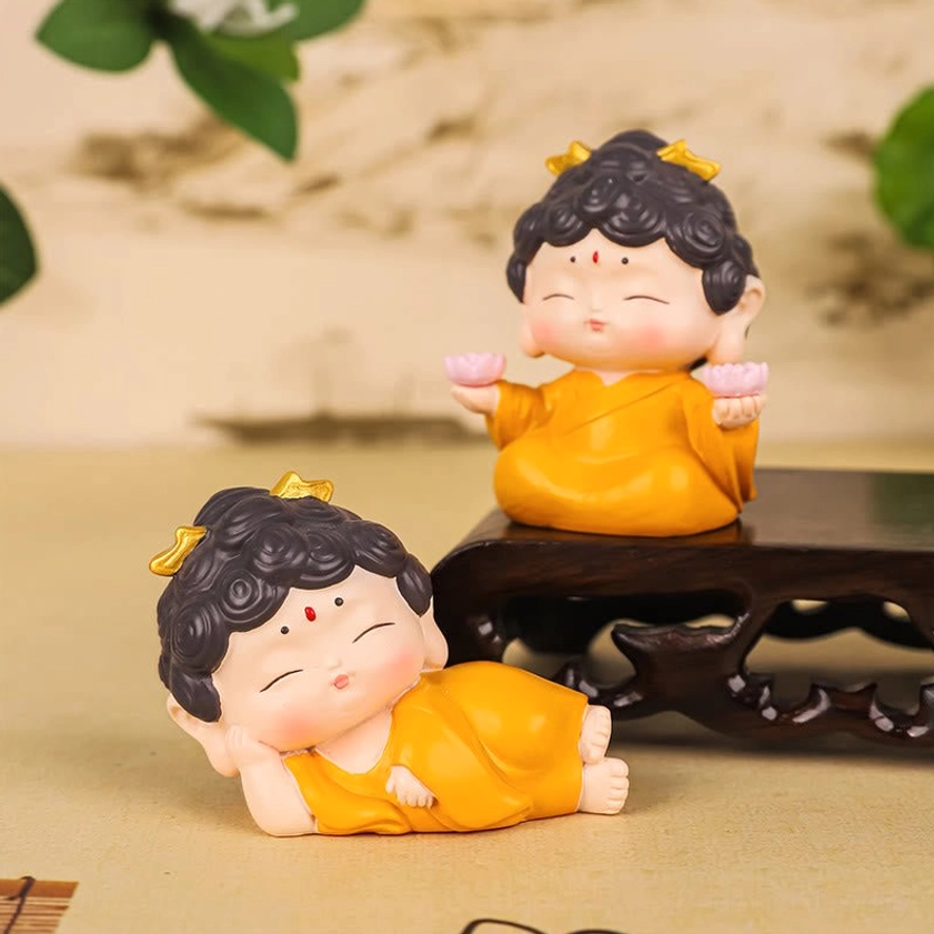 Two handcrafted resin Amitabha Buddha figurines with yellow robes and pink lotus bases on meditation desktop display
