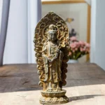 Handmade Amitabha Buddha trinity iron powder resin statue with rustic weathered patina finish, showcasing intricate carved backplate and ornate Buddhist iconography on wooden table