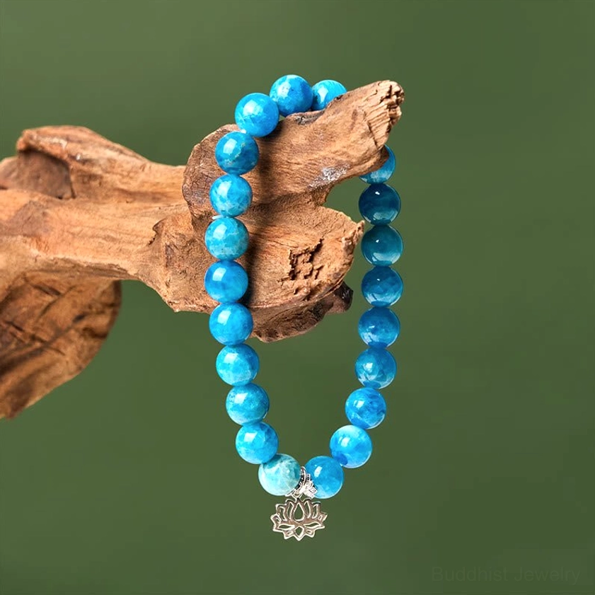Apatite lotus bracelet hanging on driftwood display, showcasing the beaded design and silver lotus charm in bohemian style setting