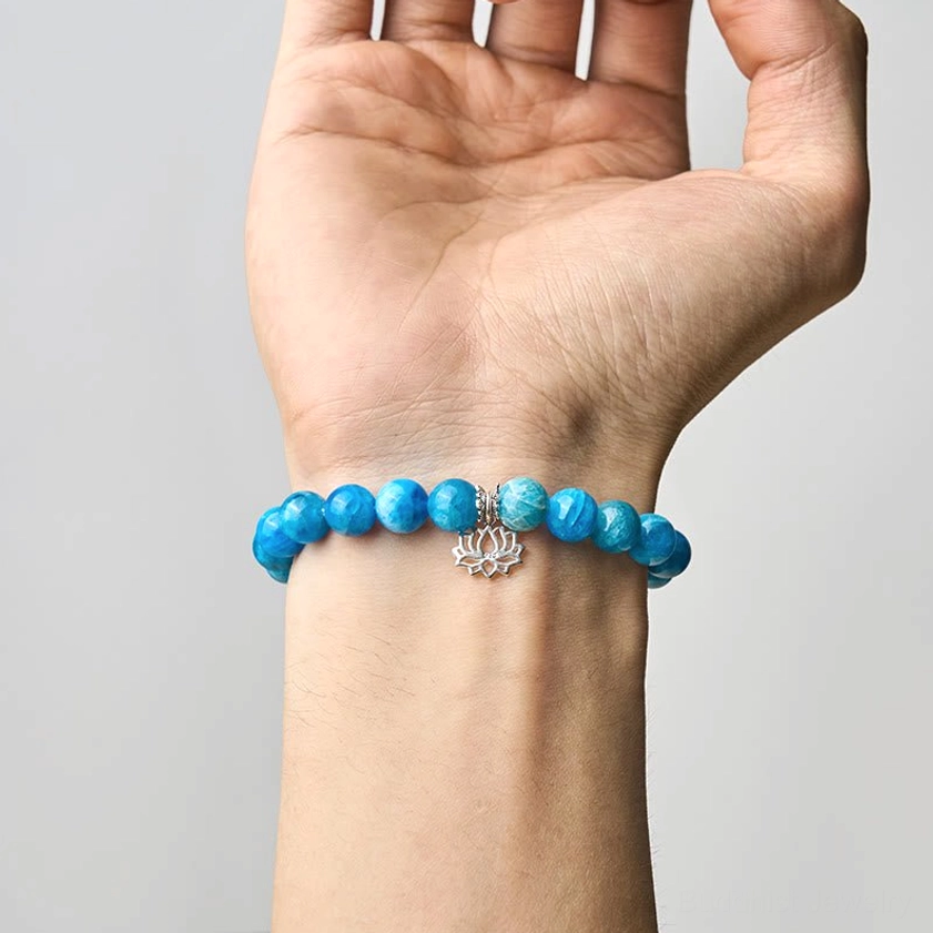 Apatite lotus bracelet worn on wrist, close-up showing proper fit and comfort of the blue gemstone beads with sterling silver charm
