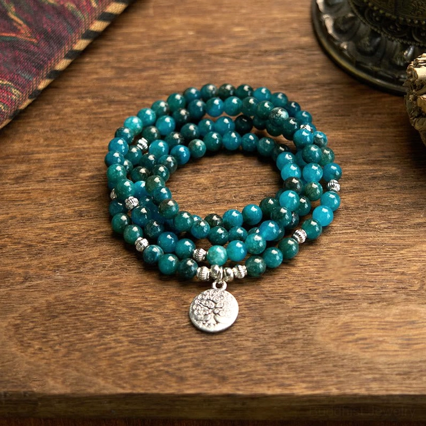 Apatite mala bracelet with Tree of Life medallion charm, teal blue beads and silver spacers on wooden desktop