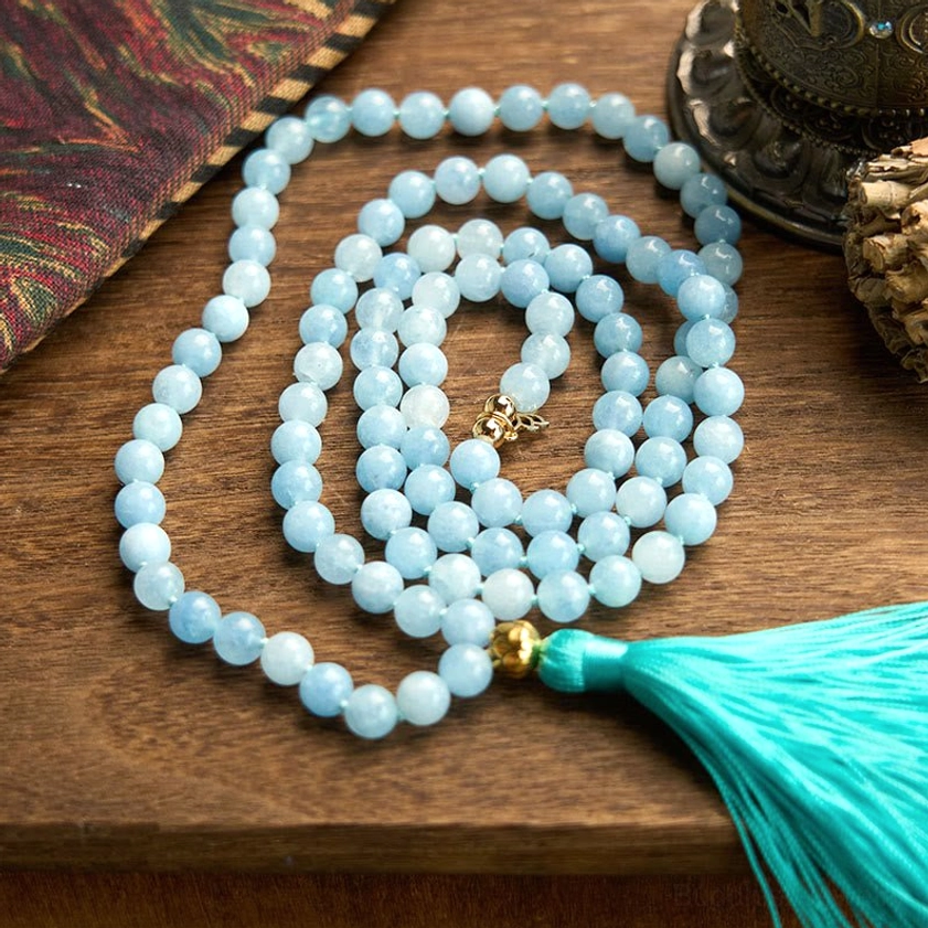 Aquamarine 108 mala beads coiled display with silver lotus metal charm and turquoise tassel