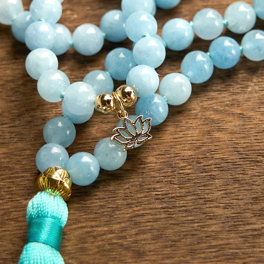 Macro close-up of smooth round aquamarine mala beads with gold and silver metal accents