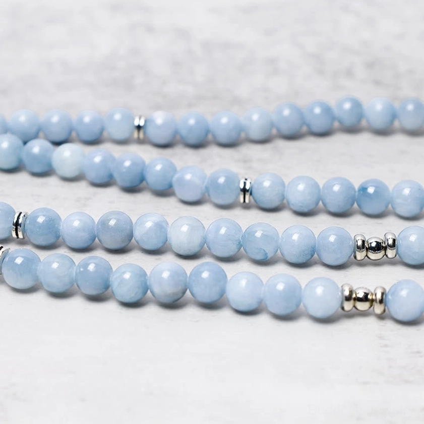 Aquamarine mala bead strand side view displaying smooth round light blue crystals with silver spacer accents