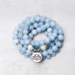 108 aquamarine mala bead bracelet overhead view with silver lotus charm on light background