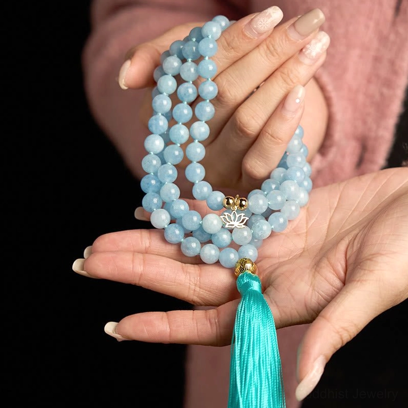 Aquamarine mala beads necklace held in both hands with silver lotus charm pendant